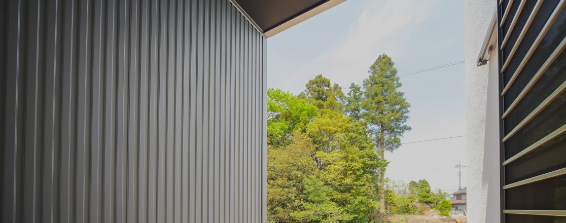 屋外から見た金属製の外壁と緑豊かな風景